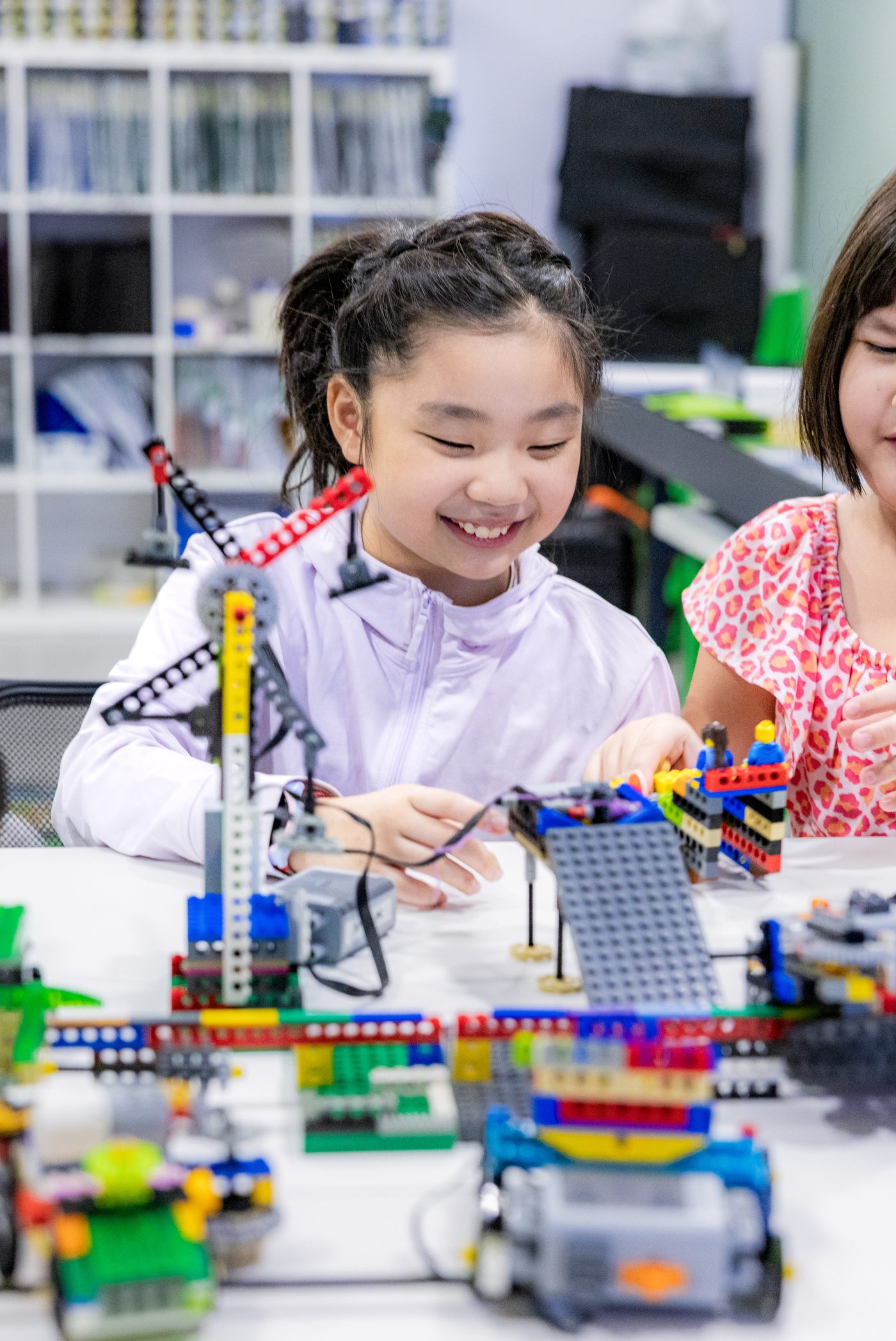 A student focused on wiring and assembling a LEGO robotics model