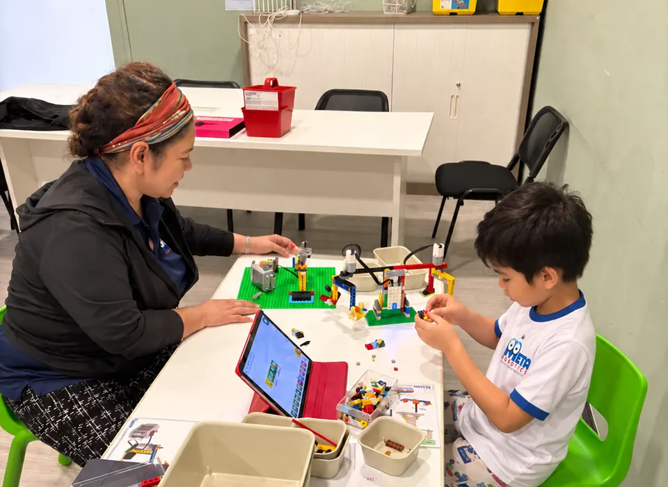 Coach guiding a High-Ranker student through a robotics building activity