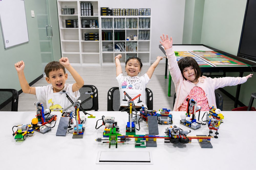 Three children celebrating their finished robot builds